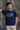 Man wearing a royal blue t-shirt with text standing against an ornate metal gate.