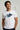 Man wearing a white t-shirt with a blue graphic and text, standing against a plain background.