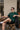 Man wearing a bottle green 'New York' t-shirt sitting outdoors.