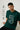 Man wearing a bottle green t-shirt with text and graphics, sitting against a white background.