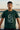 Man wearing a bottle green t-shirt with text standing in front of a vintage car.