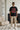 Man wearing a black t-shirt with graphic design in a living room.