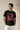 Man wearing a black t-shirt with a graphic design and text, standing against a plain background.
