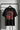 Black t-shirt with red and white graphic design on a hanger against a gray background