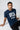 Man wearing a pastel blue t-shirt with 'SFCA' printed on it against a white background