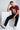 Man sitting on a white cube wearing a maroon red t-shirt with text and graphics, black pants, and white sneakers.
