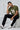 Man sitting on a white block wearing a olive t-shirt with text and graphics.