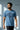 Man wearing a light blue t-shirt with a graphic design against a gray background