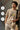 Man wearing a 'Wanderlust' t-shirt with nature graphic, holding a coffee cup, standing against a textured wall.