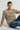Man wearing a light beige t-shirt with 'Wanderlust' and mountain graphic on a light gray background