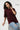 Woman wearing an oversized maroon red t-shirt with red text and light blue jeans on a white background.